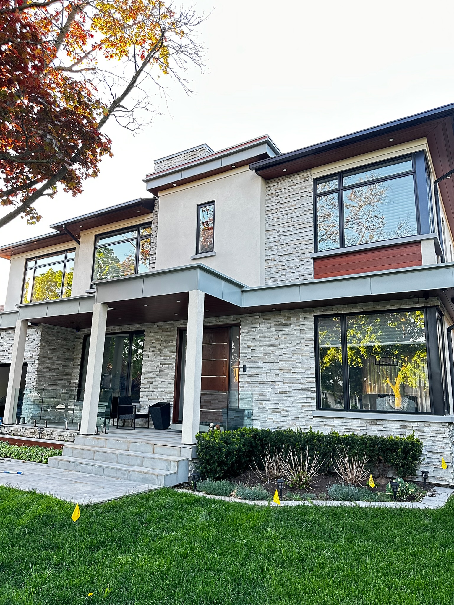 Modern stone home frontage with clean black-framed windows and glass railing