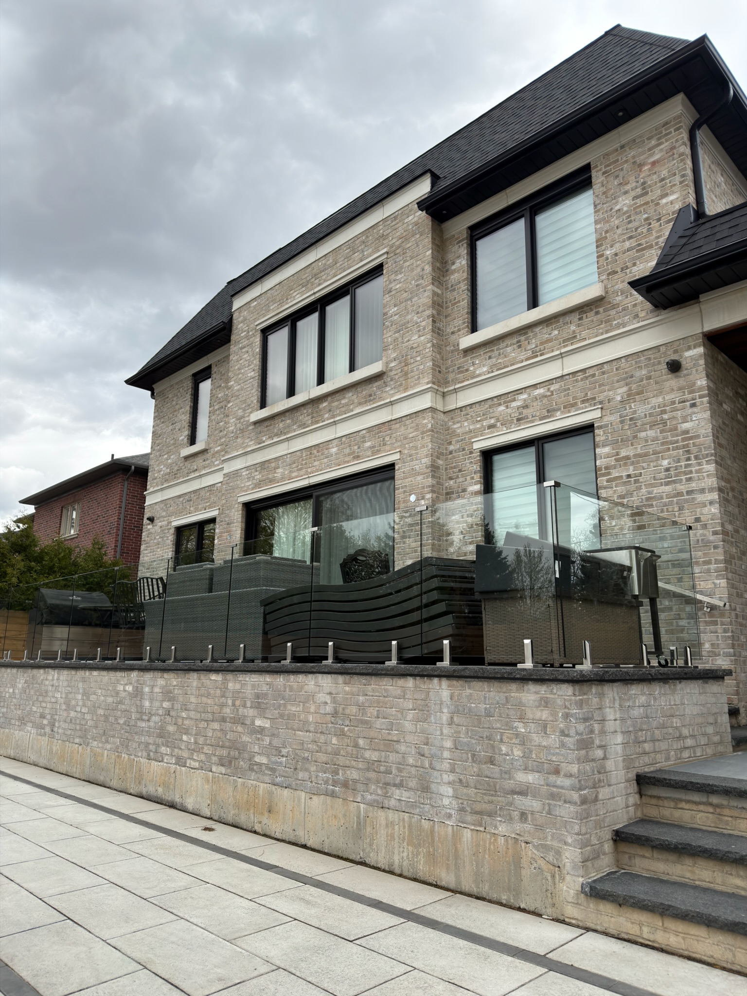 Brick home patio with clean upper windows and glass deck railing